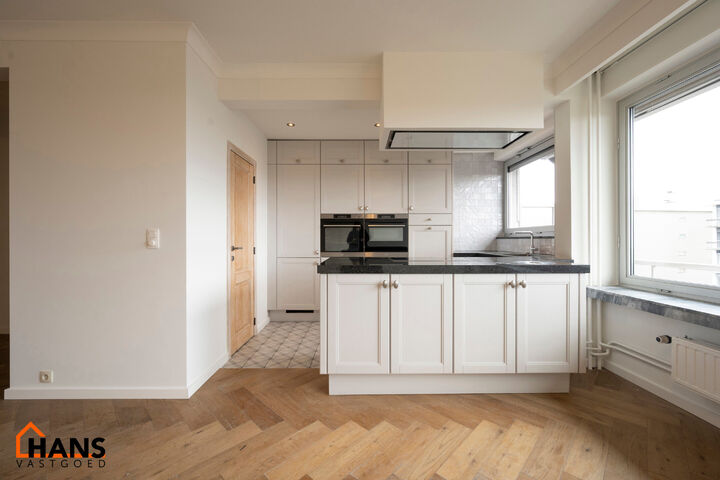 Instapklaar appartement op de zesde verdieping met garagebox omvat inkom met vestiairekast; woonkamer; open en ge&iuml;nstalleerde keuken met toestellen: koelkast, vriezer, kookplaat op inductie, vaatwasser, dampkap combioven, oven, kasten, spoelbak en een ex