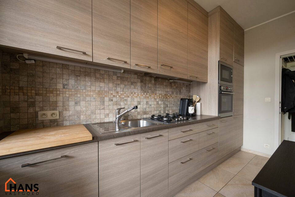 Inkomhal; leefruimte; keuken met vele kasten, lades, gasvuur, dampkap; spoelbak, oven, microgolf, vaatwasser en koelkast, toegang tot achterliggend terras; berging met aansluiting voor wasmachine en droogkast; badkamer met ruime douche, wastafel in meubel