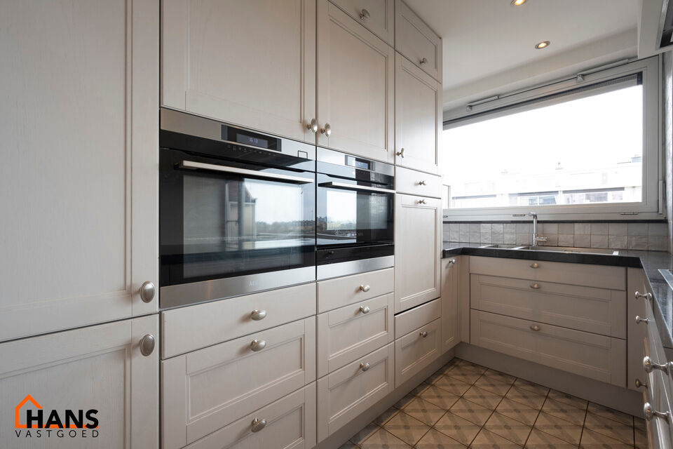 Instapklaar appartement op de zesde verdieping met garagebox omvat inkom met vestiairekast; woonkamer; open en ge&iuml;nstalleerde keuken met toestellen: koelkast, vriezer, kookplaat op inductie, vaatwasser, dampkap combioven, oven, kasten, spoelbak en een ex