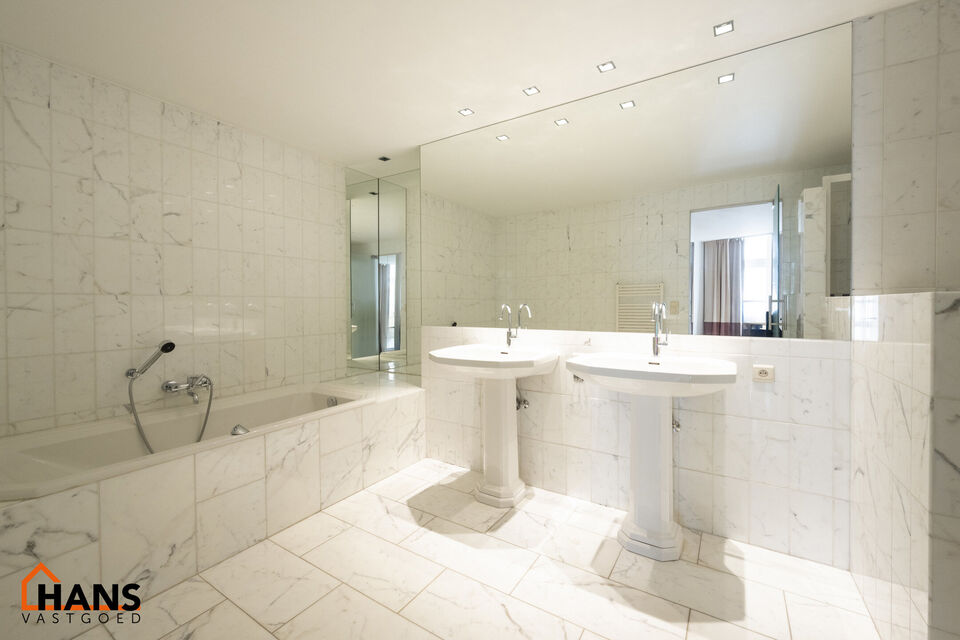 Inkomhal met vestiairekast; apart toilet met wastafel; riante, lichtrijke woonkamer van 80m² op een houten vloer met ingemaakte kasten; ruime keuken, volledig ingericht met kasten, lades en alle toestellen (gasfornuis, dampkap, vaatwasser, combi-oven, ko