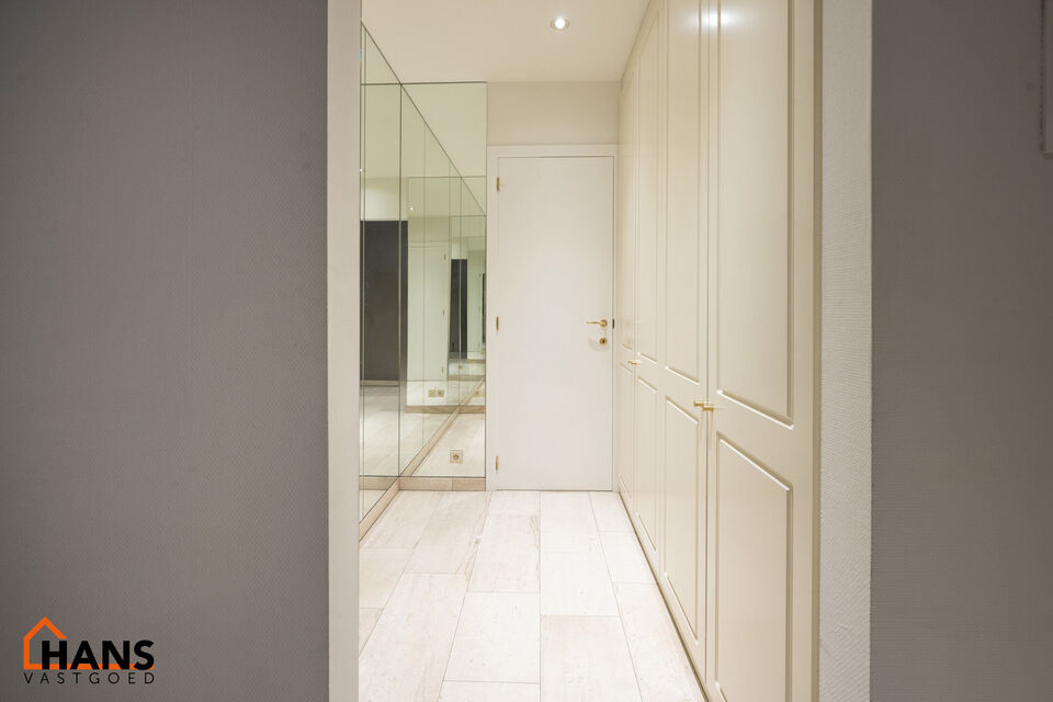Inkomhal met vestiairekast; apart toilet met wastafel; riante, lichtrijke woonkamer van 80m² op een houten vloer met ingemaakte kasten; ruime keuken, volledig ingericht met kasten, lades en alle toestellen (gasfornuis, dampkap, vaatwasser, combi-oven, ko