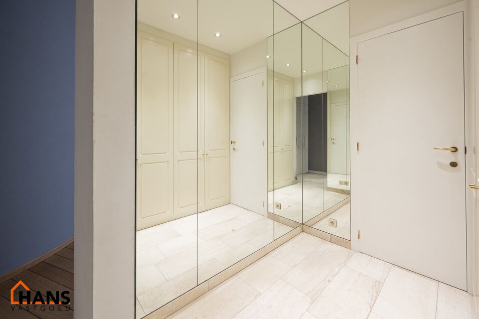 Inkomhal met vestiairekast; apart toilet met wastafel; riante, lichtrijke woonkamer van 80m² op een houten vloer met ingemaakte kasten; ruime keuken, volledig ingericht met kasten, lades en alle toestellen (gasfornuis, dampkap, vaatwasser, combi-oven, ko