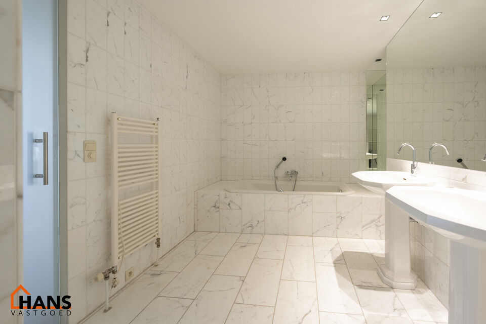 Inkomhal met vestiairekast; apart toilet met wastafel; riante, lichtrijke woonkamer van 80m² op een houten vloer met ingemaakte kasten; ruime keuken, volledig ingericht met kasten, lades en alle toestellen (gasfornuis, dampkap, vaatwasser, combi-oven, ko
