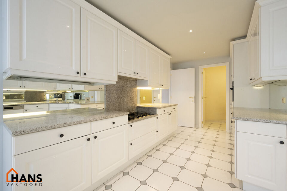 Inkomhal met vestiairekast; apart toilet met wastafel; riante, lichtrijke woonkamer van 80m² op een houten vloer met ingemaakte kasten; ruime keuken, volledig ingericht met kasten, lades en alle toestellen (gasfornuis, dampkap, vaatwasser, combi-oven, ko