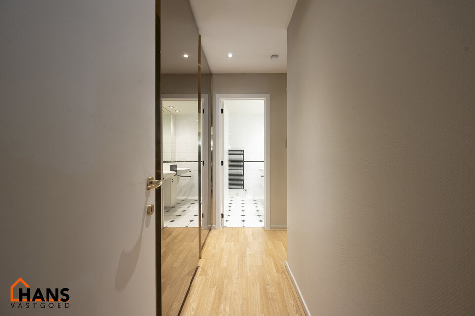 Inkomhal met vestiairekast; apart toilet met wastafel; riante, lichtrijke woonkamer van 80m² op een houten vloer met ingemaakte kasten; ruime keuken, volledig ingericht met kasten, lades en alle toestellen (gasfornuis, dampkap, vaatwasser, combi-oven, ko