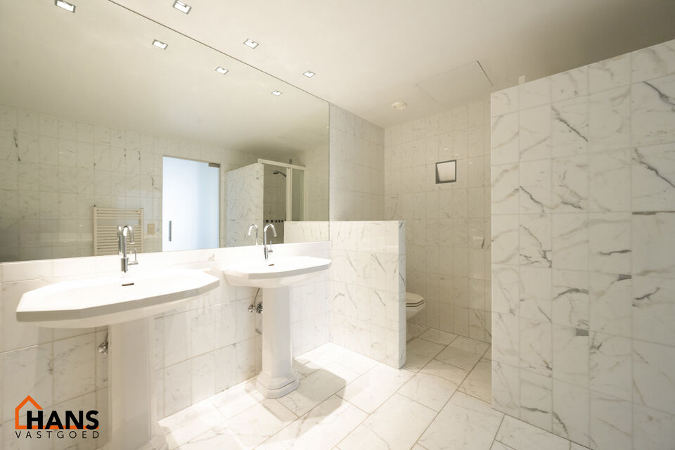 Inkomhal met vestiairekast; apart toilet met wastafel; riante, lichtrijke woonkamer van 80m² op een houten vloer met ingemaakte kasten; ruime keuken, volledig ingericht met kasten, lades en alle toestellen (gasfornuis, dampkap, vaatwasser, combi-oven, ko